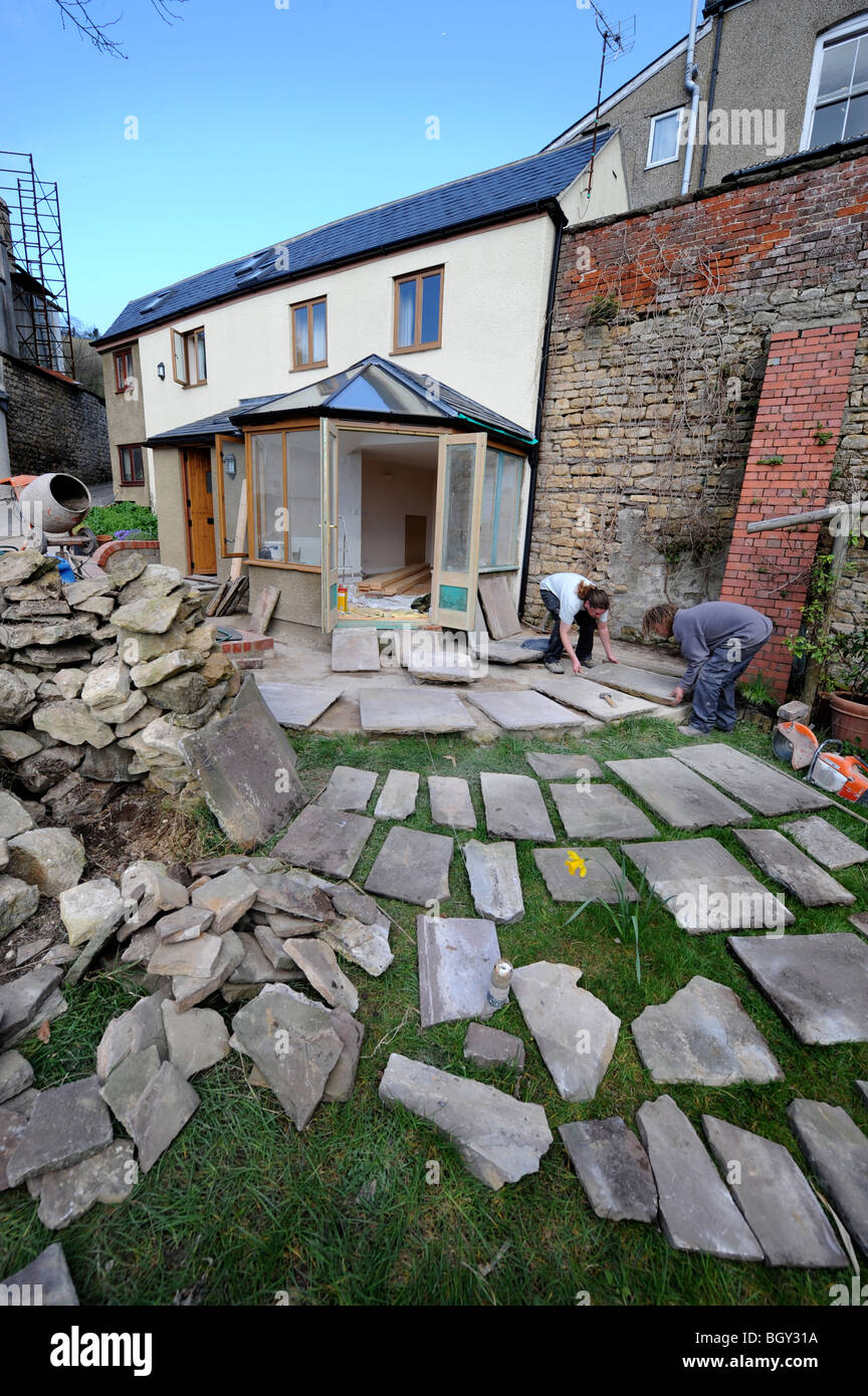 Les constructeurs de dalles de pierres naturelles dans la planification d'un patio, Gloucestershire UK Banque D'Images