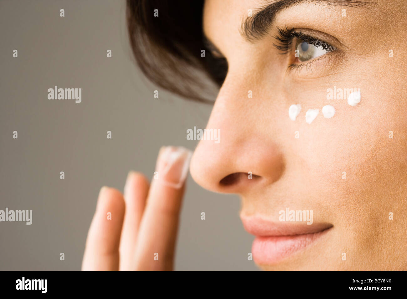 Young woman applying undereye cream Banque D'Images