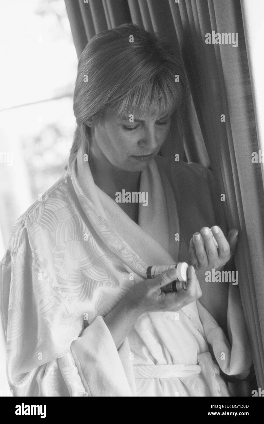 Woman looking at bottle of pills Banque D'Images