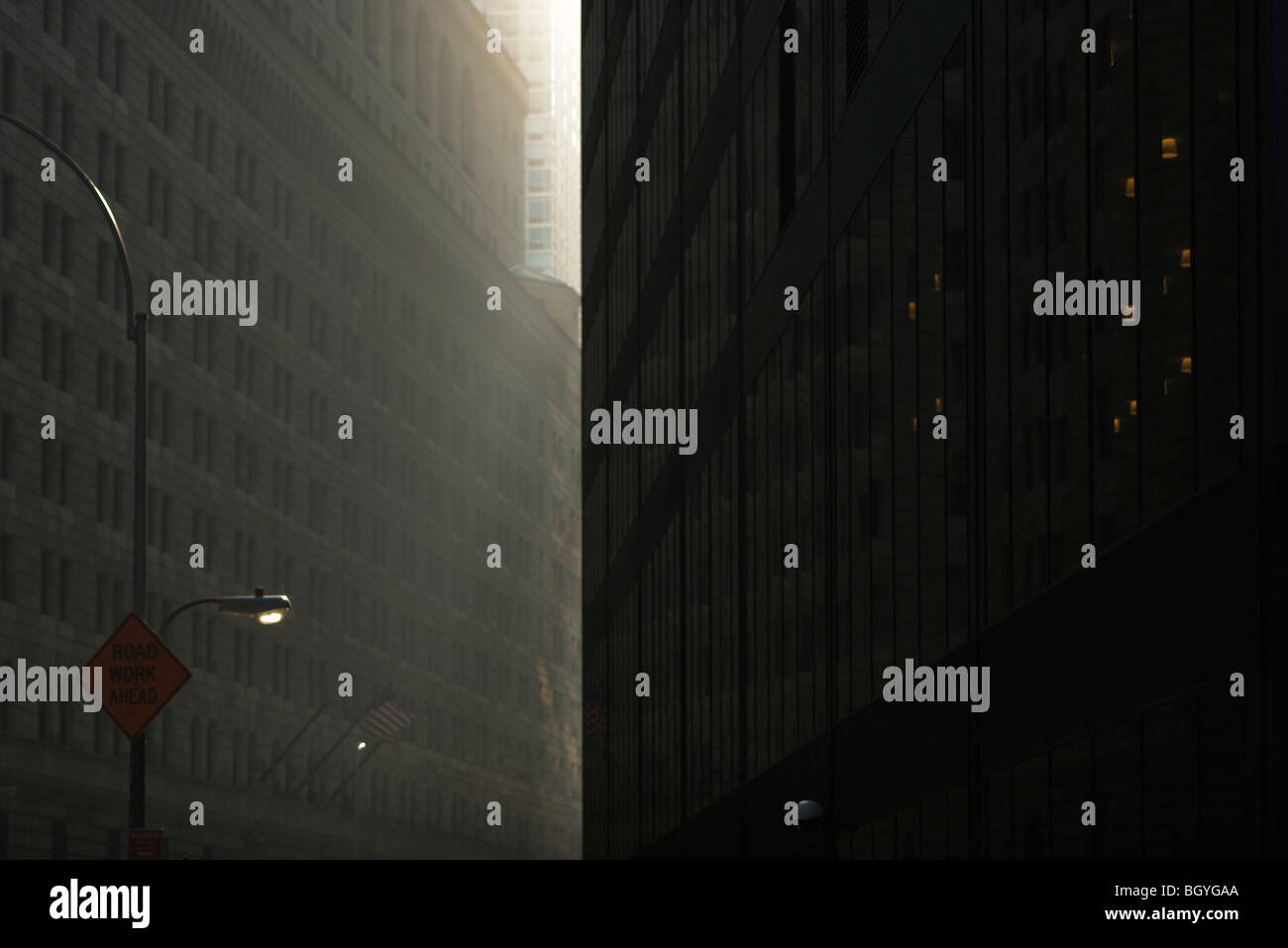 Tôt le matin, la lumière du soleil éclairant les rues de la ville sombre caché entre des tours imposantes, NYC, NY Banque D'Images