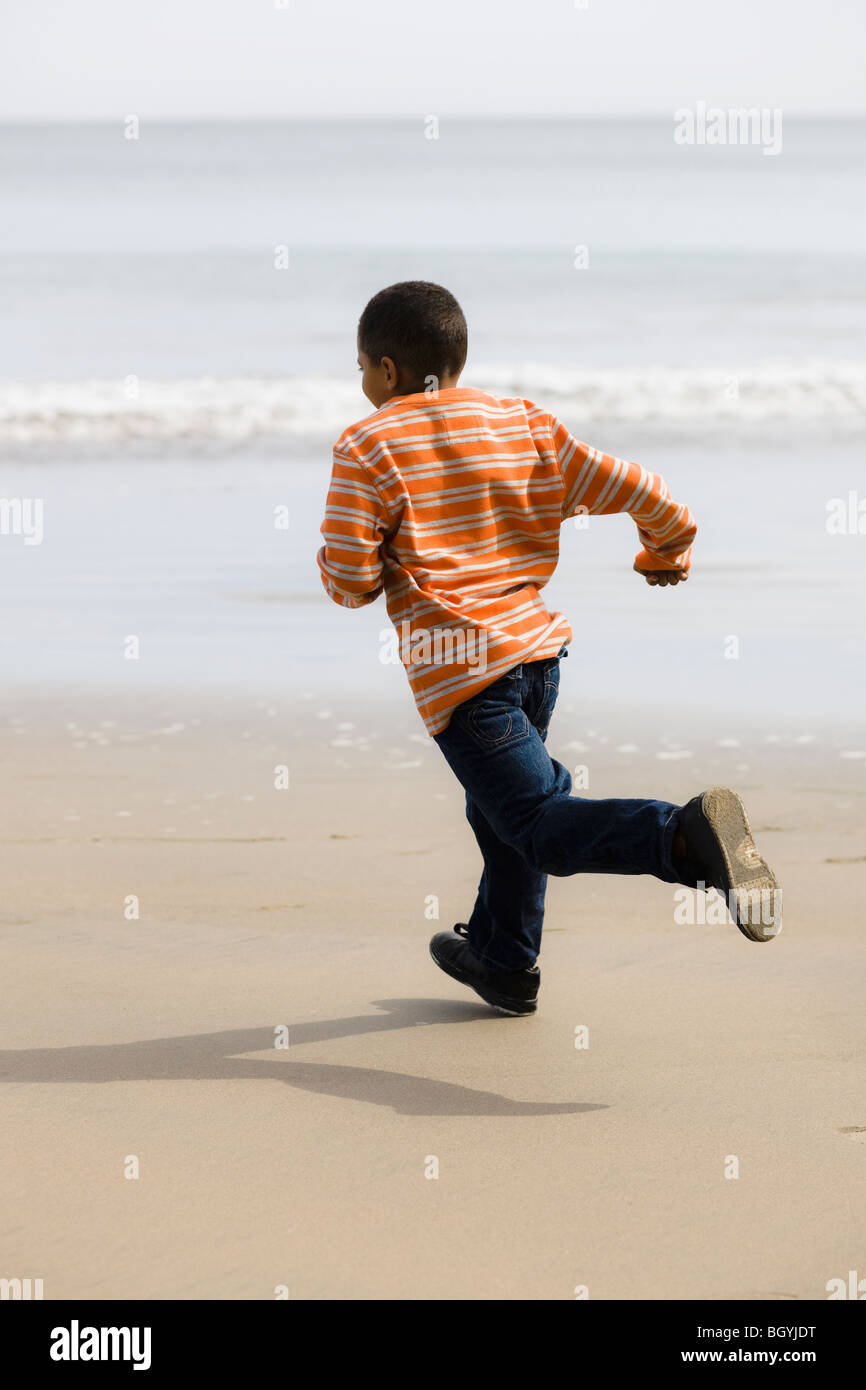 Jeune garçon running on beach Banque D'Images