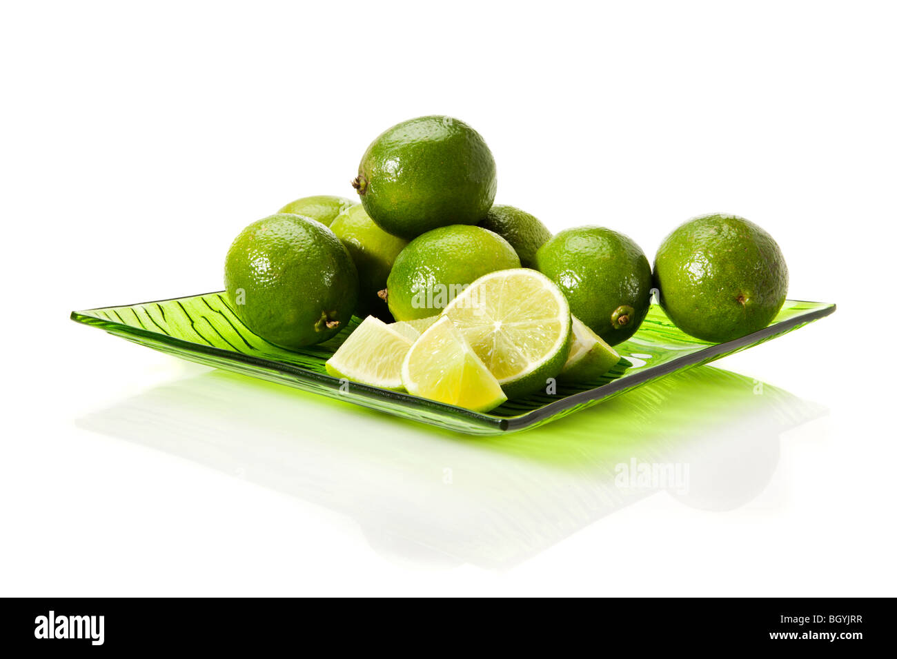 Limes fraîches sur plaque de verre vert isolé sur fond blanc Banque D'Images