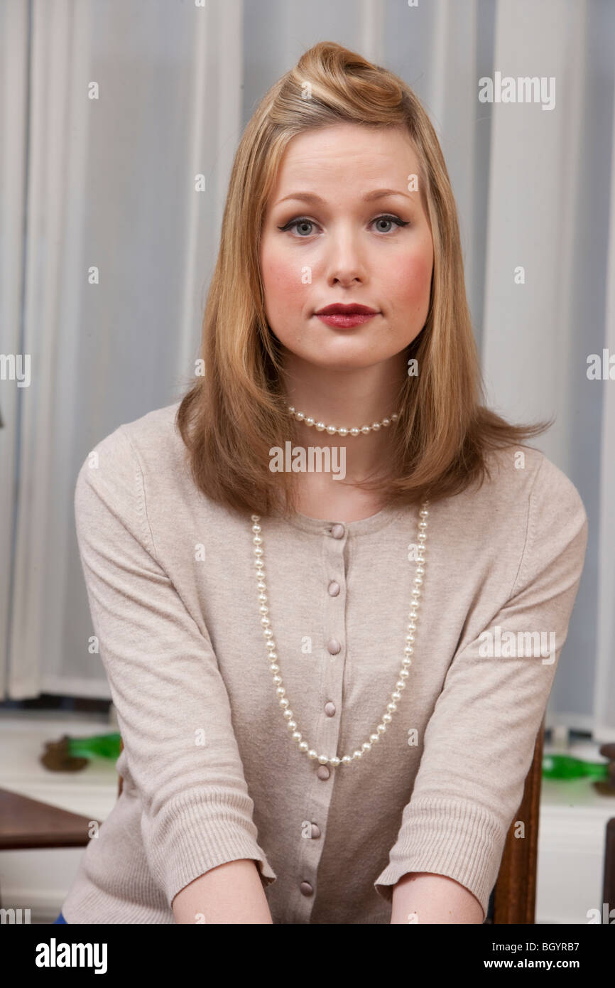 Jolie jeune blonde wearing cardigan et collier de perles Banque D'Images