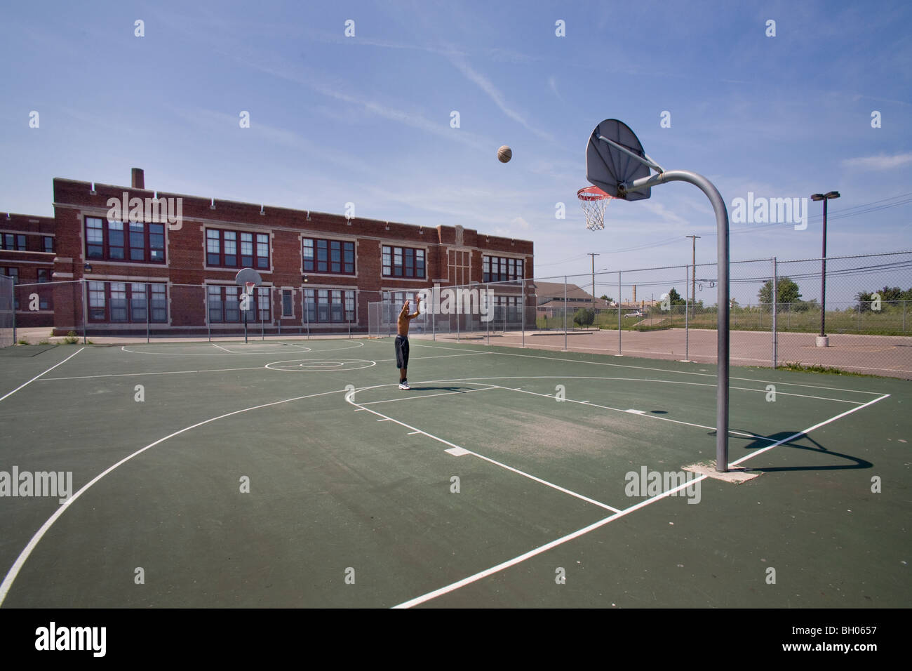 Un joueur solitaire pratiques au basket-ball d'une fermeture de l'école secondaire de Detroit pendant la haute industrie automobile le chômage. Banque D'Images