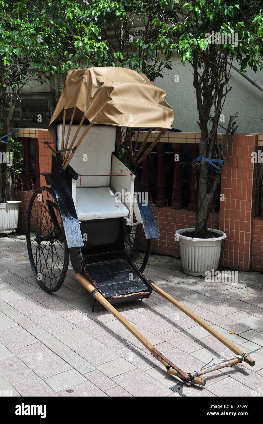 Un pousse-pousse, avec roues à rayons et hotte marron, stationné à l'extérieur d'un magasin de souvenirs, Stanley Market, Stanley, Hong Kong Banque D'Images