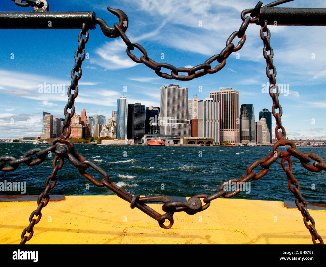 La partie inférieure du quartier financier de Manhattan sont vus à travers les chaînes de sécurité de la Governor's Island dans le port de New York. Banque D'Images