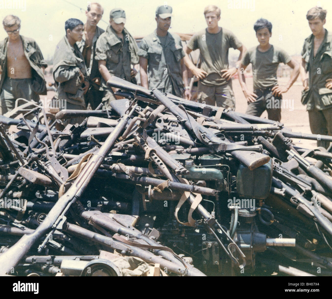 Personnel à Quan Li regarder par-dessus la zone d'atterrissage et assortiment d'armes ennemies acheminé par hélicoptère du Cambodge Banque D'Images