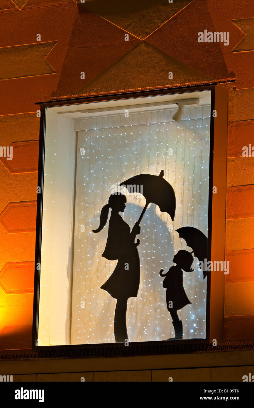 Affichage vitrine montrant une silhouette d'une femme et de la jeune fille qui détiennent chacun un parapluie dans la Ville de München (Munich), la Bavière Banque D'Images