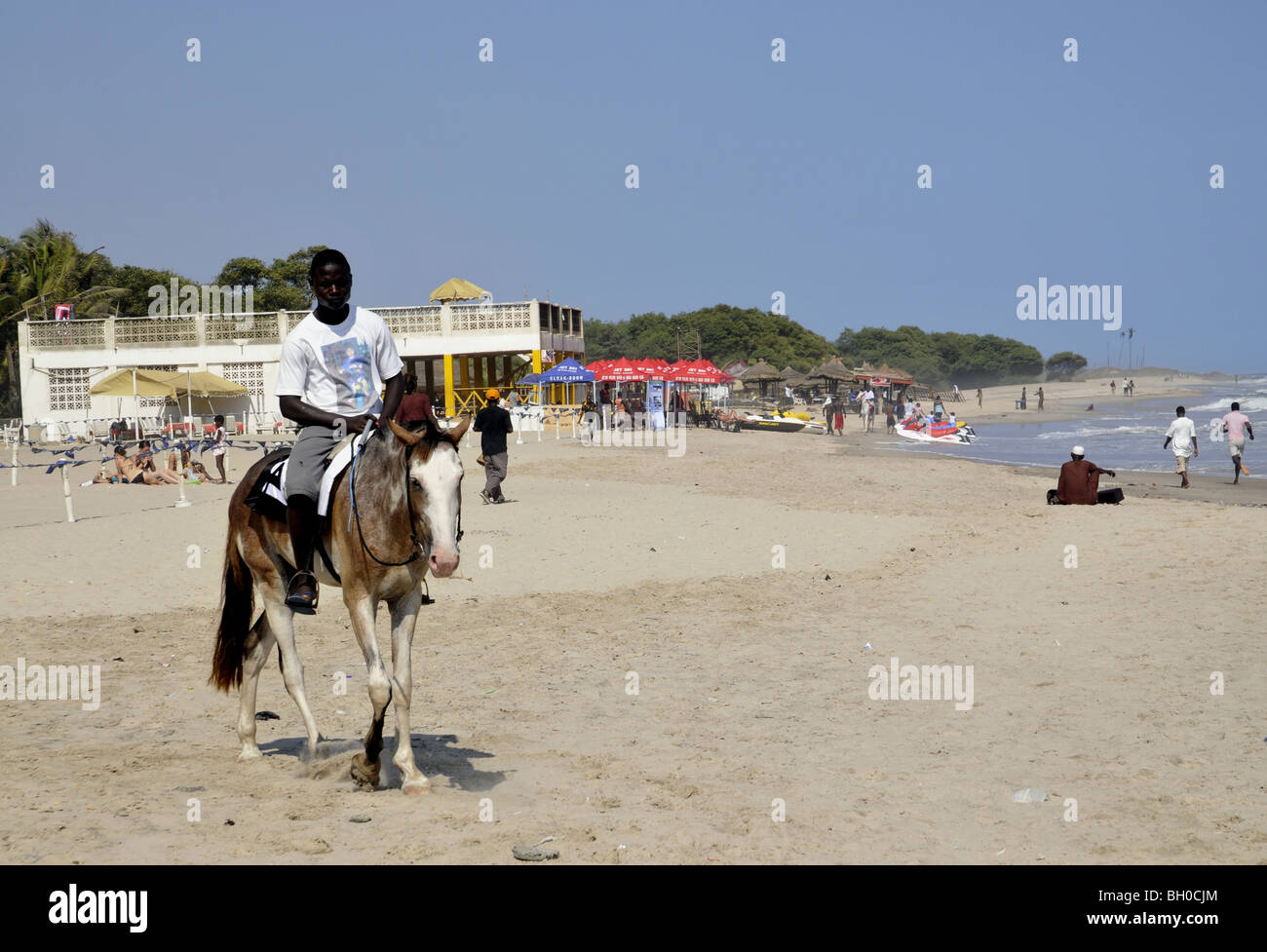 Un homme monte un cheval sur une plage au Ghana Banque D'Images