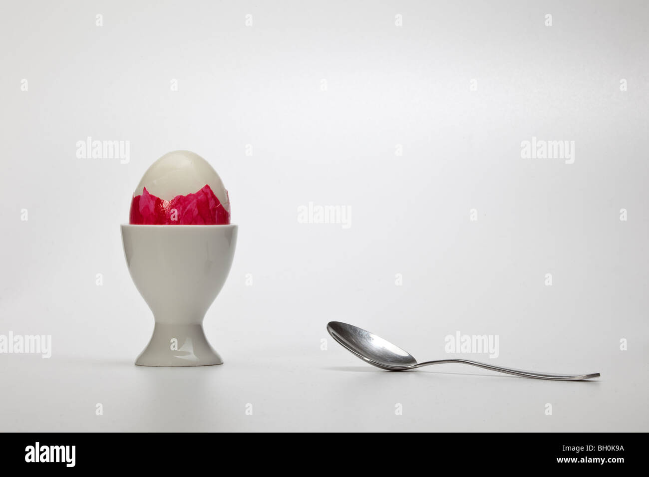 Un oeuf de Pâques dans la porcelaine coquetier avec une cuillère en métal Banque D'Images