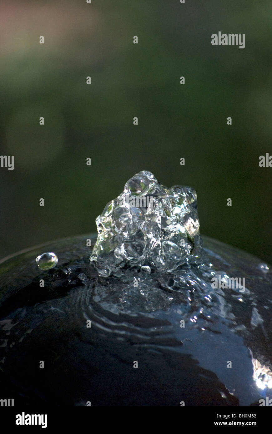 Fontaine de jardin bulles un jour d'été avec de l'eau claire, vitreux, et un vol stationnaire de gouttelette. Banque D'Images