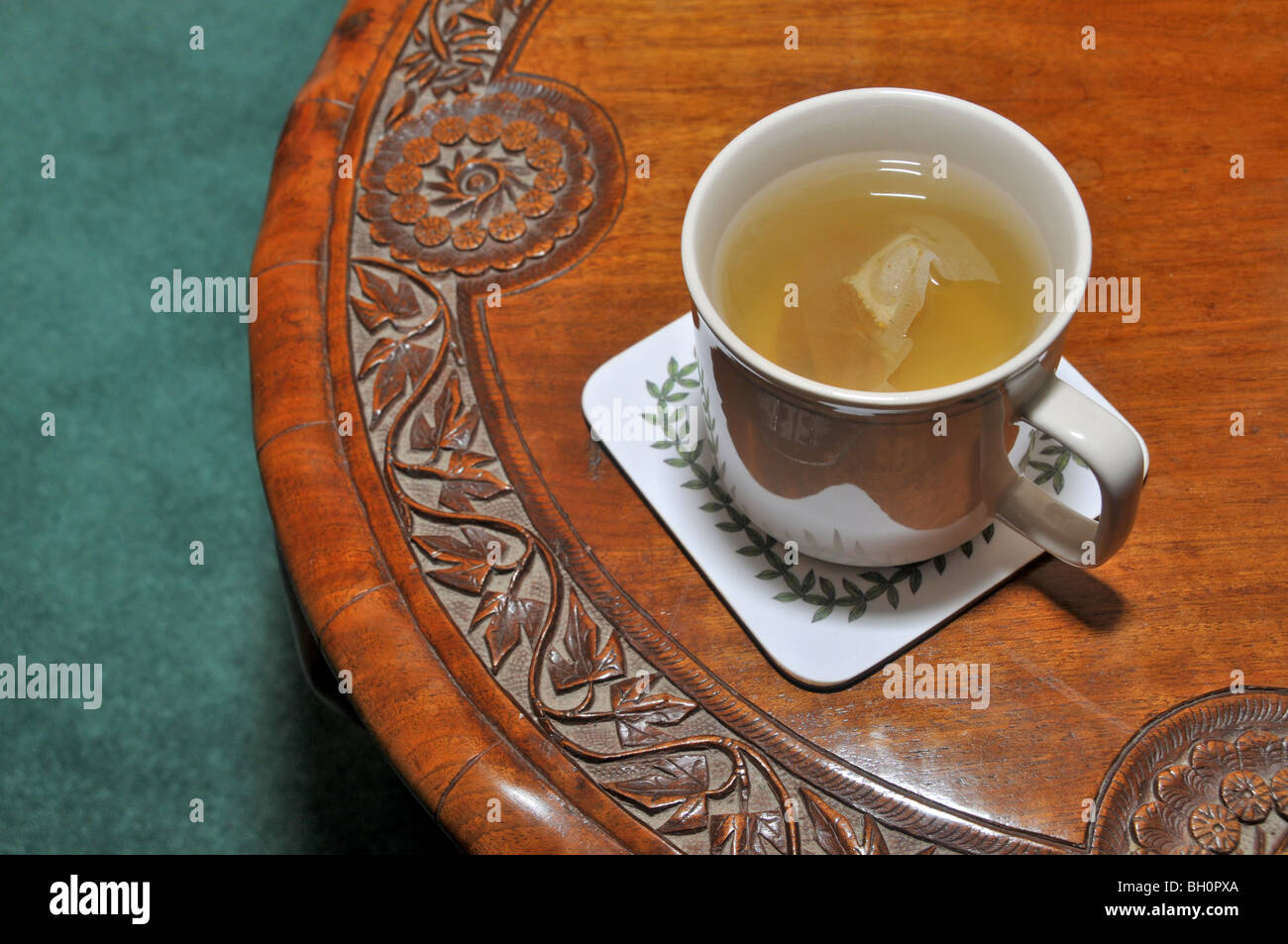 Une tasse de thé de fines herbes est assis sur une table ornée de bois. Banque D'Images
