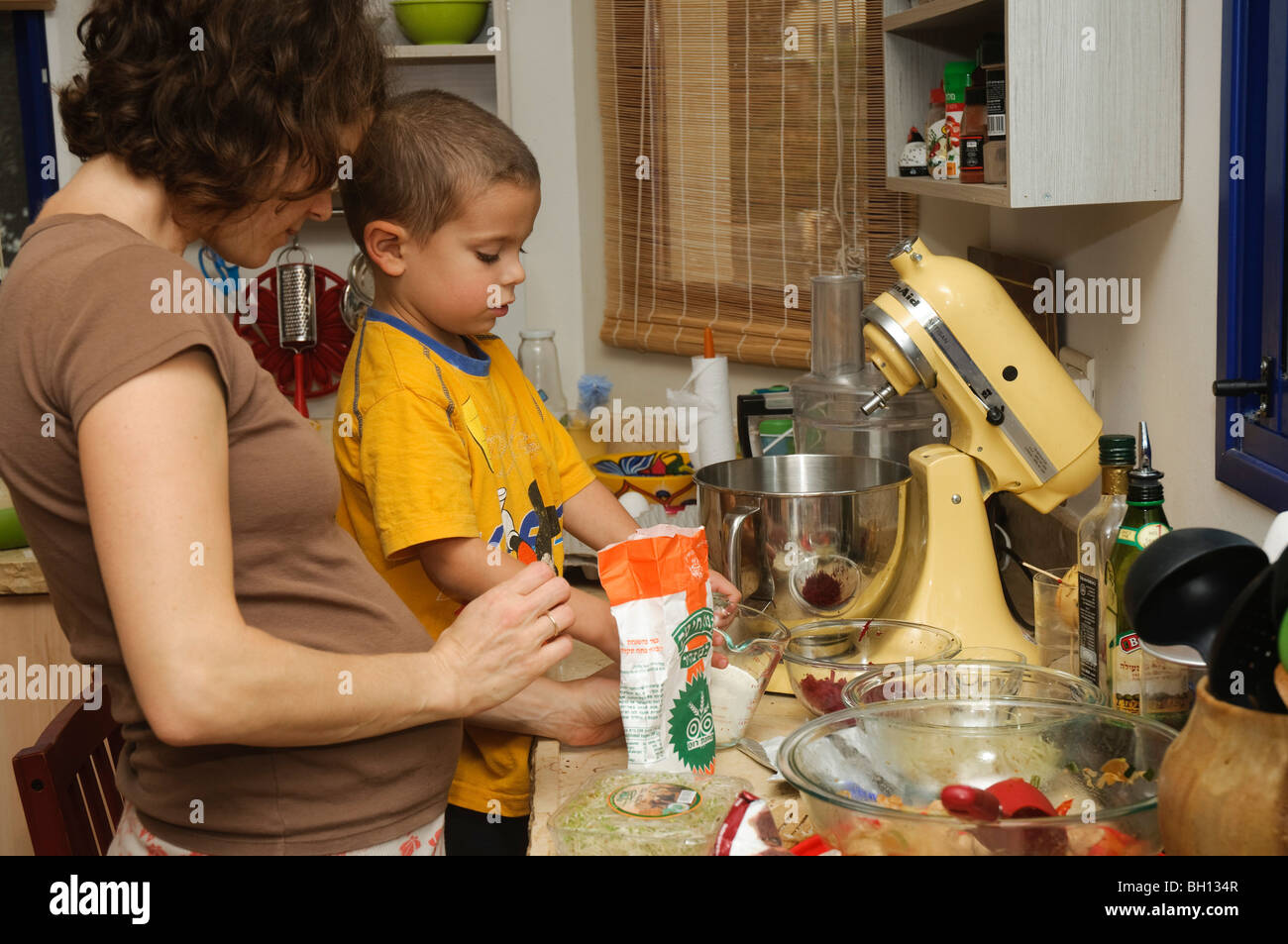 La mère et le fils travaillent ensemble dans la cuisine la sauvegarde d'un gâteau - autorisation Modèle disponible Banque D'Images