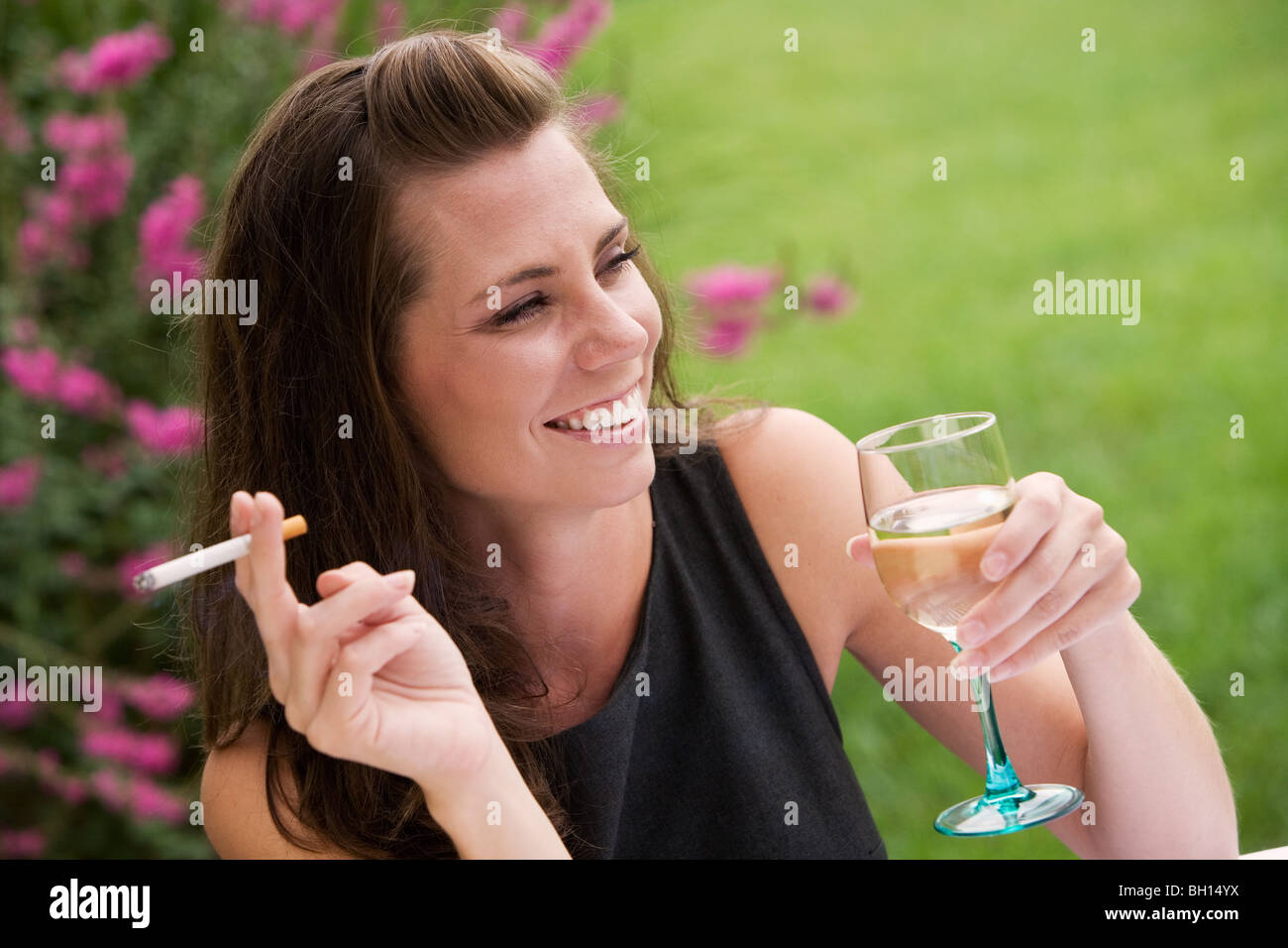 Jeune femme se détendre avec un verre de vin et une cigarette dans un café en plein air Banque D'Images