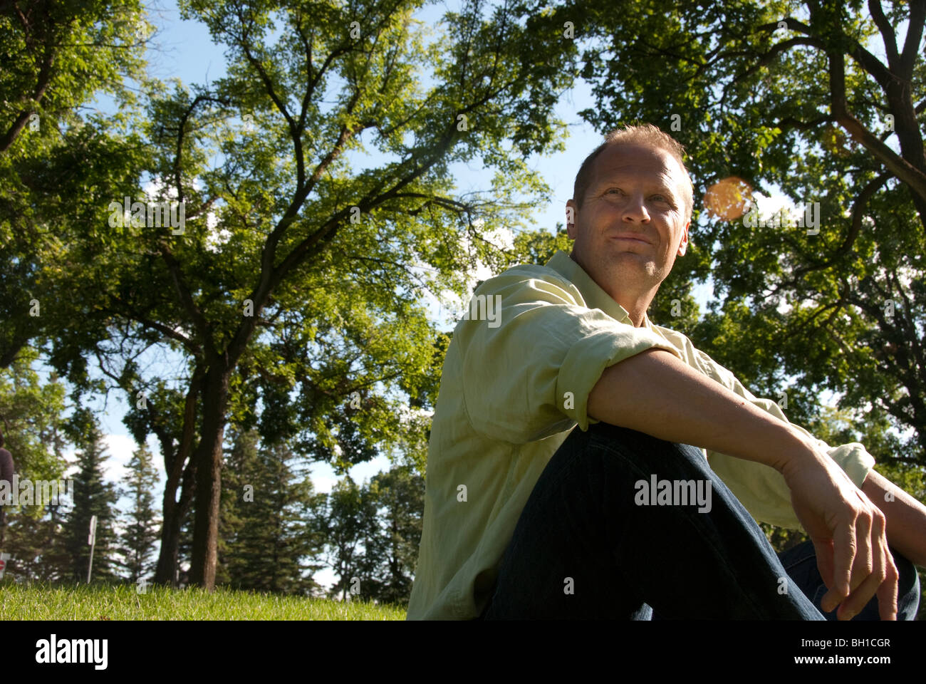 L'homme à son 40's sitting on grass dans Assinboine Park, Winnipeg, Manitoba, Canada Banque D'Images