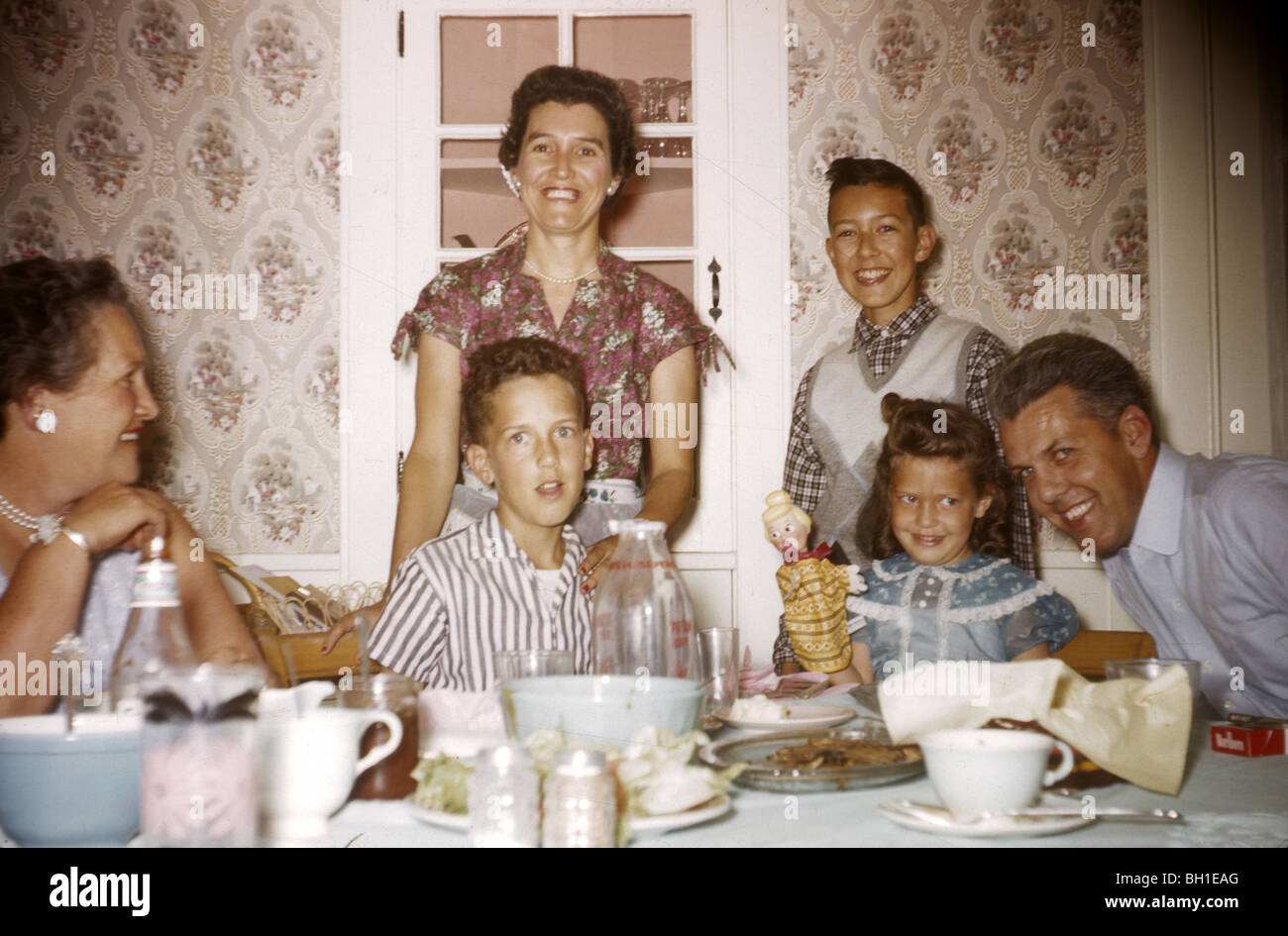 Famille à la table de dîner pendant les années 50. papier peint à l'ancienne mode portrait pose horizontale 50s coin repas ensemble sourire Banque D'Images