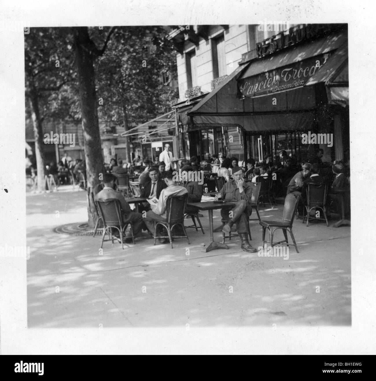Les Parisiens et les SIG assis at sidewalk cafe dans Paris libéré, la France à la fin de la DEUXIÈME GUERRE MONDIALE. Banque D'Images