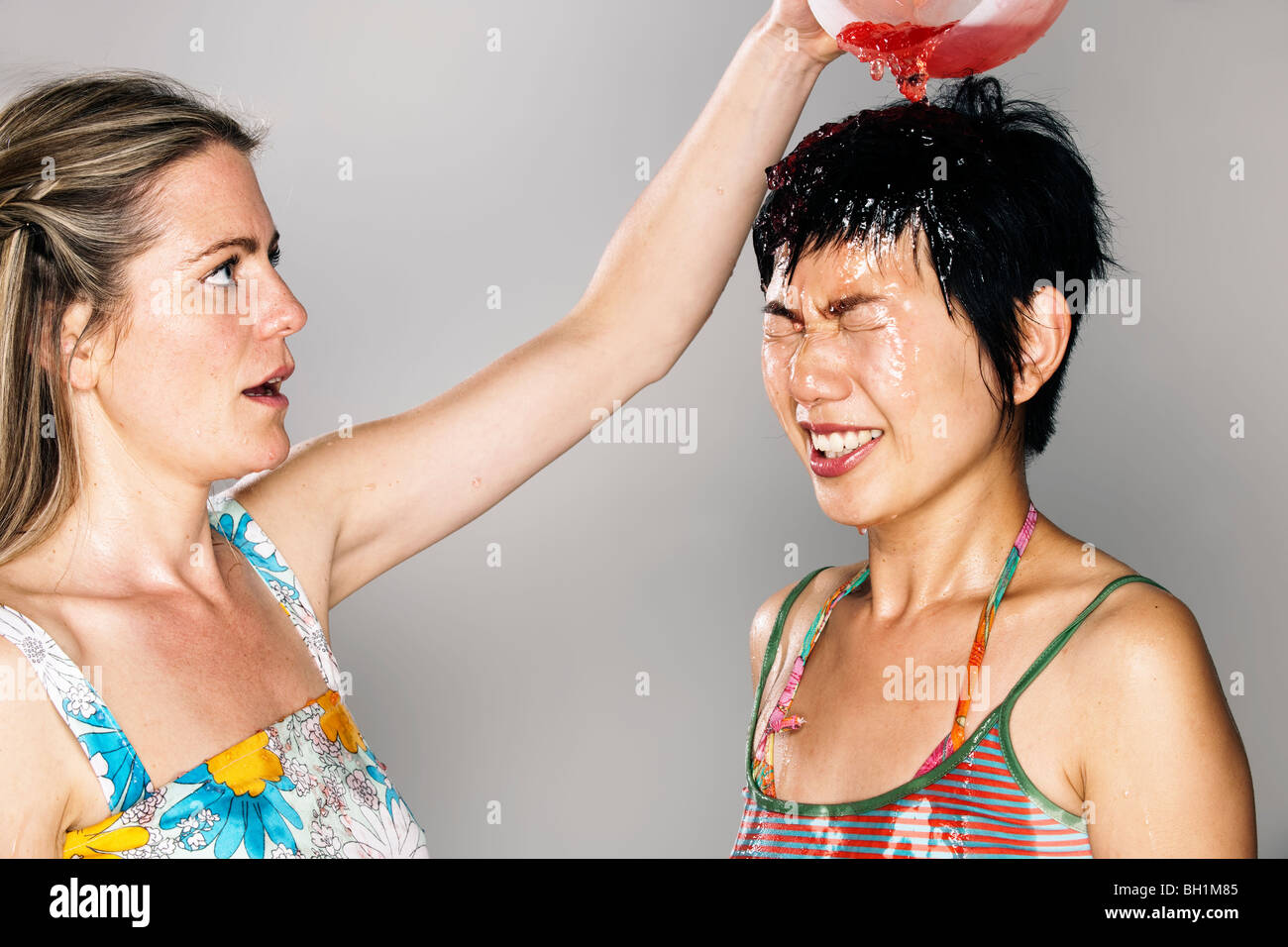 Woman pouring jelly sur la tête d'une autre femme Banque D'Images