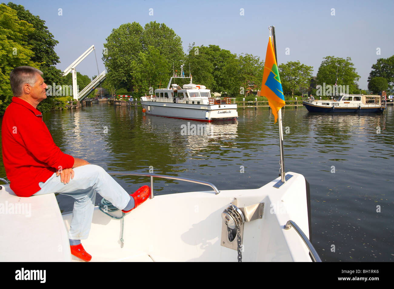 Un homme assis sur la proue d'un bateau, bateaux de la conduite sur la rivière Vecht, Pays-Bas, Europe Banque D'Images