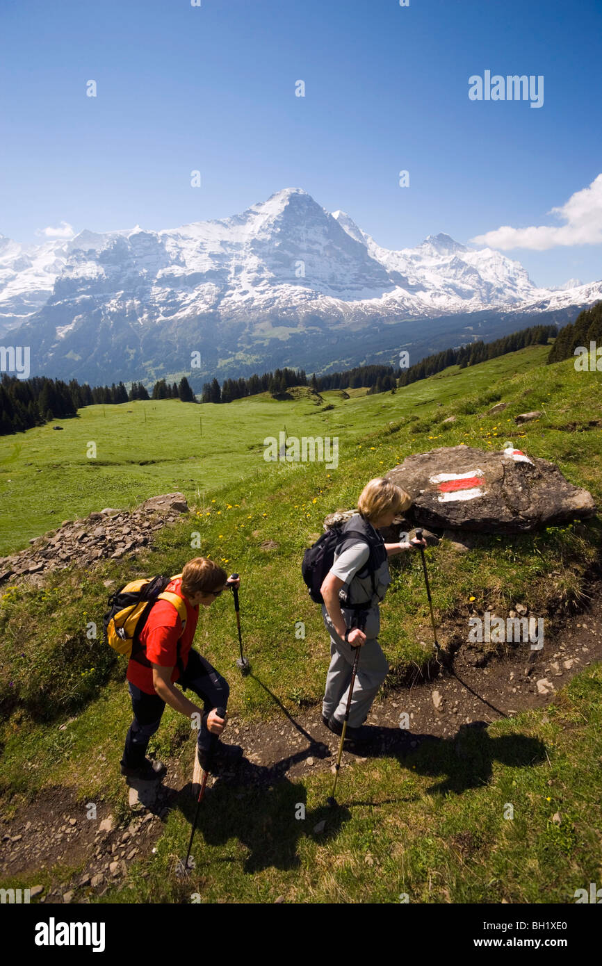 Deux personnes de la randonnée en montée à Bussalp (1800 m), vue de face nord de l'Eiger (3970 m), Grindelwald, Oberland Bernois (Highlands), Cant Banque D'Images