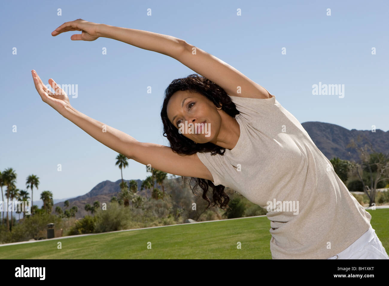 Mid adult woman stretching arms over head Banque D'Images
