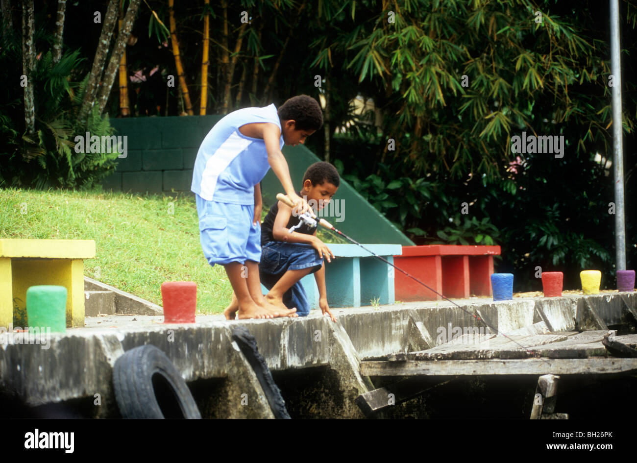 Deux garçons de la pêche dans la rivière de Tortuguero sur quai de couleur vive Banque D'Images