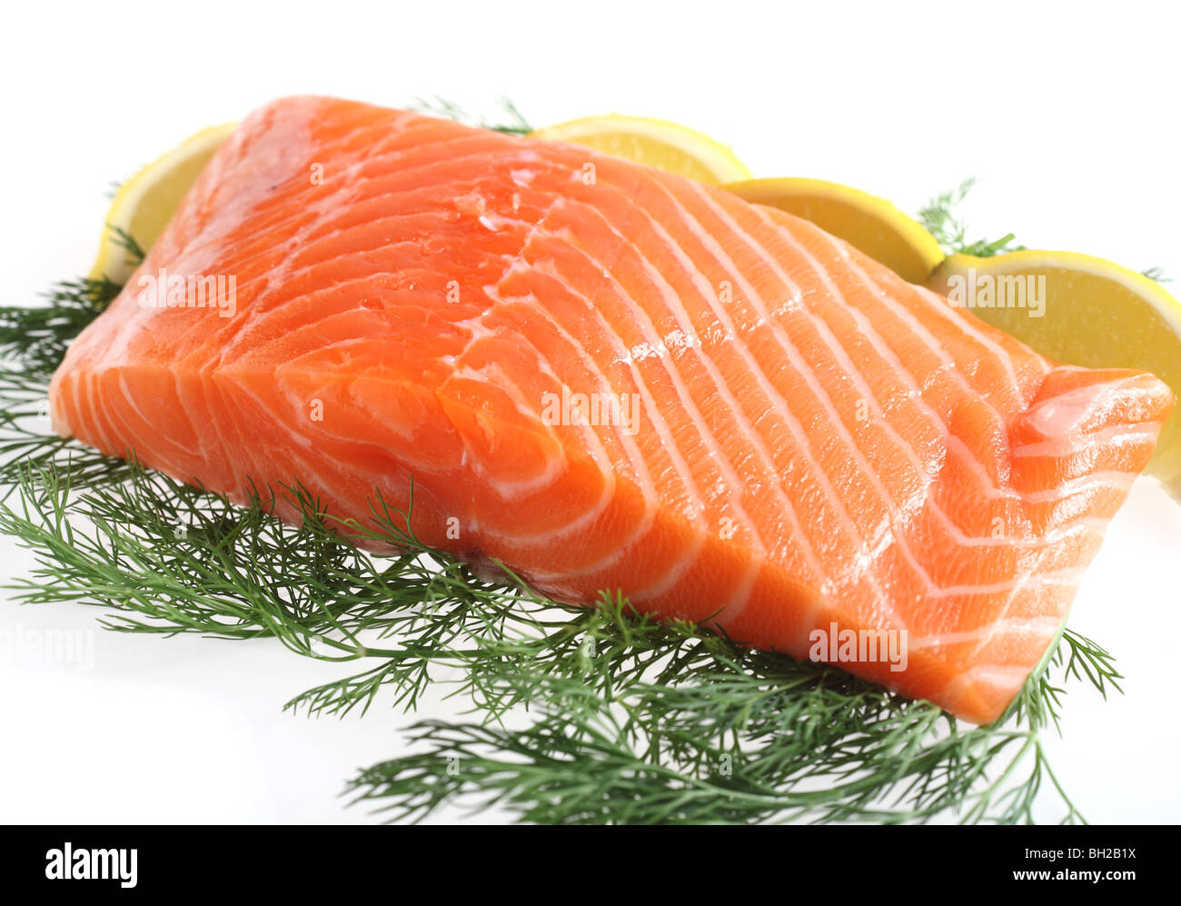 Un filet de saumon avec des quartiers de citron et l'aneth sur un fond blanc. Banque D'Images