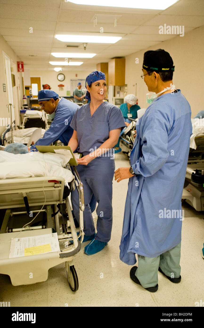 Une femme parle avec son médecin anesthésiste sur un patient précédent comme elle l'écrit et l'histoire d'un patient physique Banque D'Images