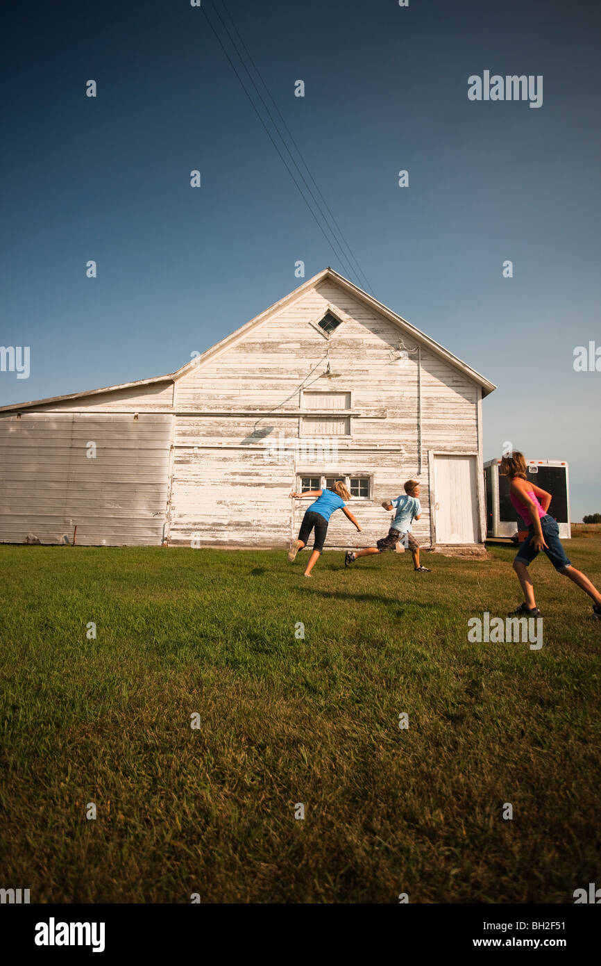 Cousins (Dix, Douze et Douze) Jouer au Tag ; basse-cour Redvers, Saskatchewan, Canada Banque D'Images