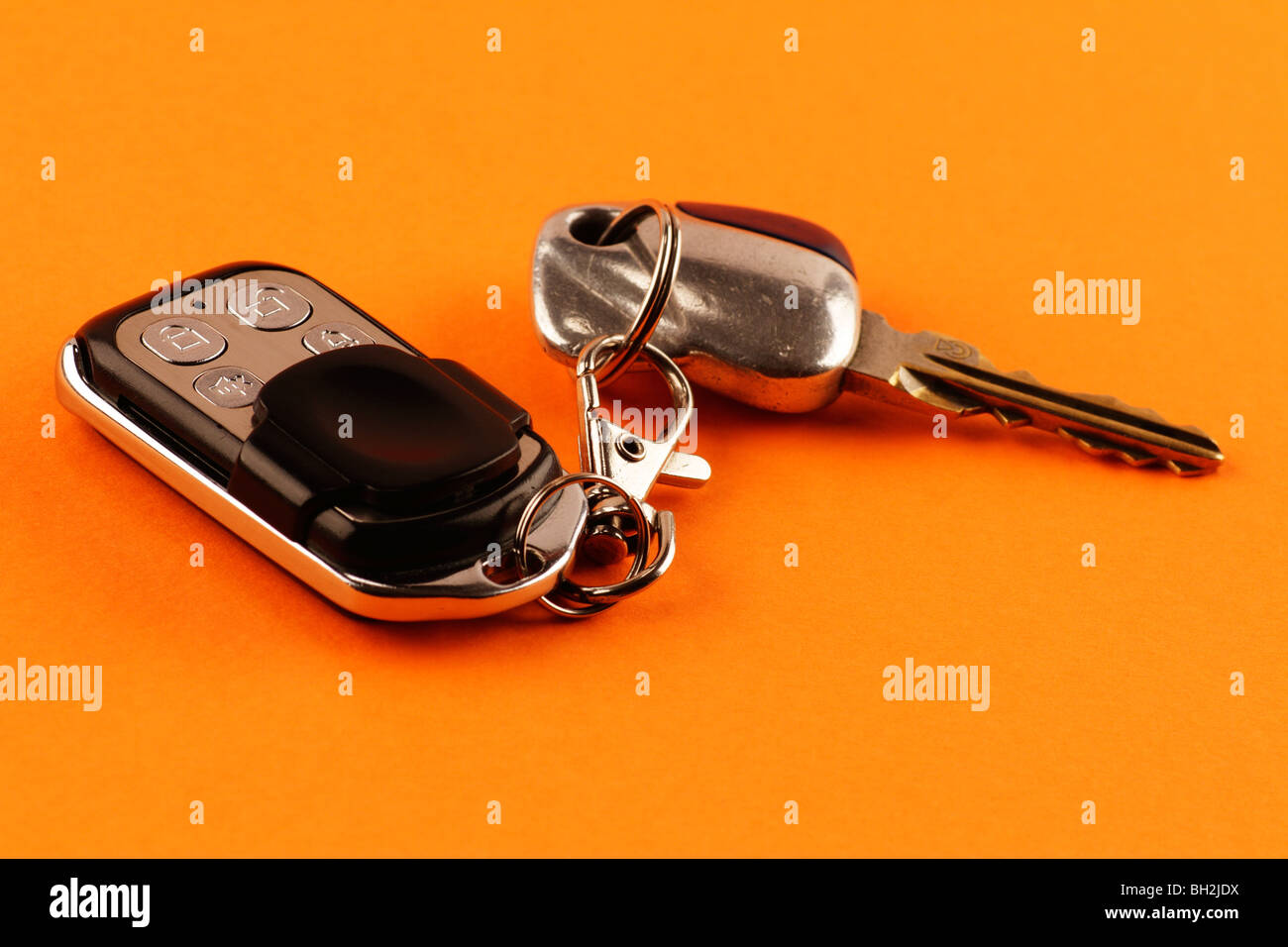 Close-up d'une télécommande d'alarme de voiture et clés de voiture sur fond orange Banque D'Images