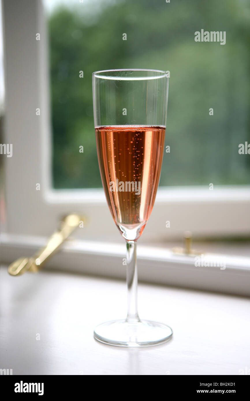 Verre de champagne rose à côté d'une fenêtre ouverte Banque D'Images