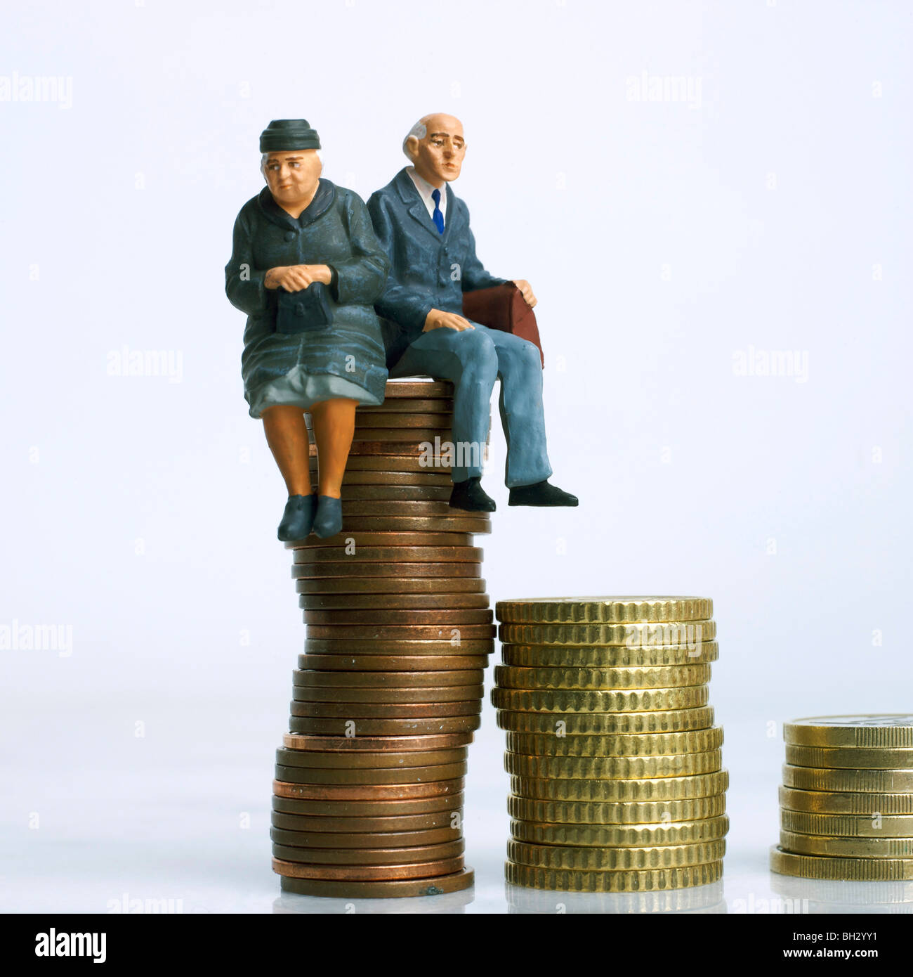 Couple de personnes âgées assis sur le dessus des pièces représentant l'épargne et la planification financière pour la retraite Banque D'Images