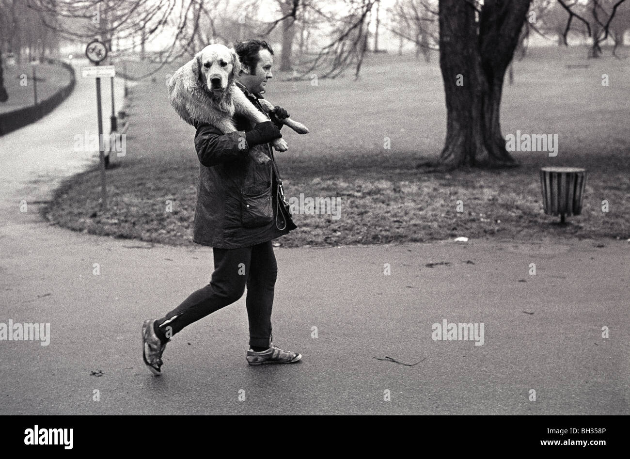 Meilleur ami du Mans. Homme marchant avec le chien Hyde Park London, portant un vieux chien sur ses épaules. ANNÉES 1979 1970 ROYAUME-UNI HOMER SYKES Banque D'Images