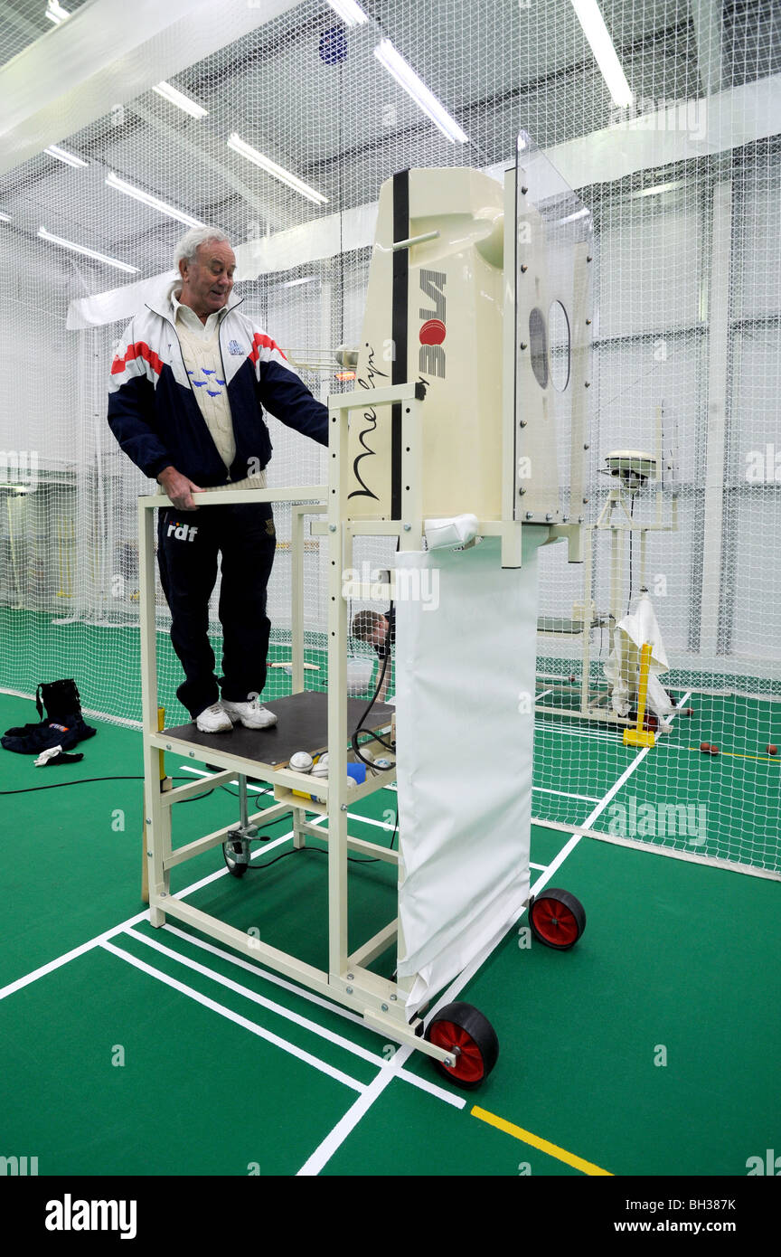 L'entraîneur de cricket de Sussex en utilisant Merlyn par BOLA bowling spin machine dans la pratique à l'école à l'intérieur de filets Banque D'Images