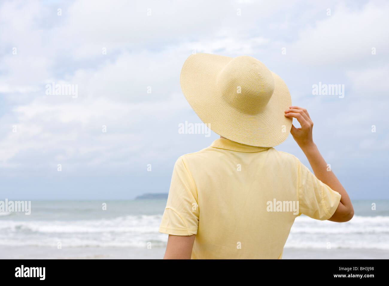 Femme avec chapeau jaune et une chemise sur une plage Banque D'Images