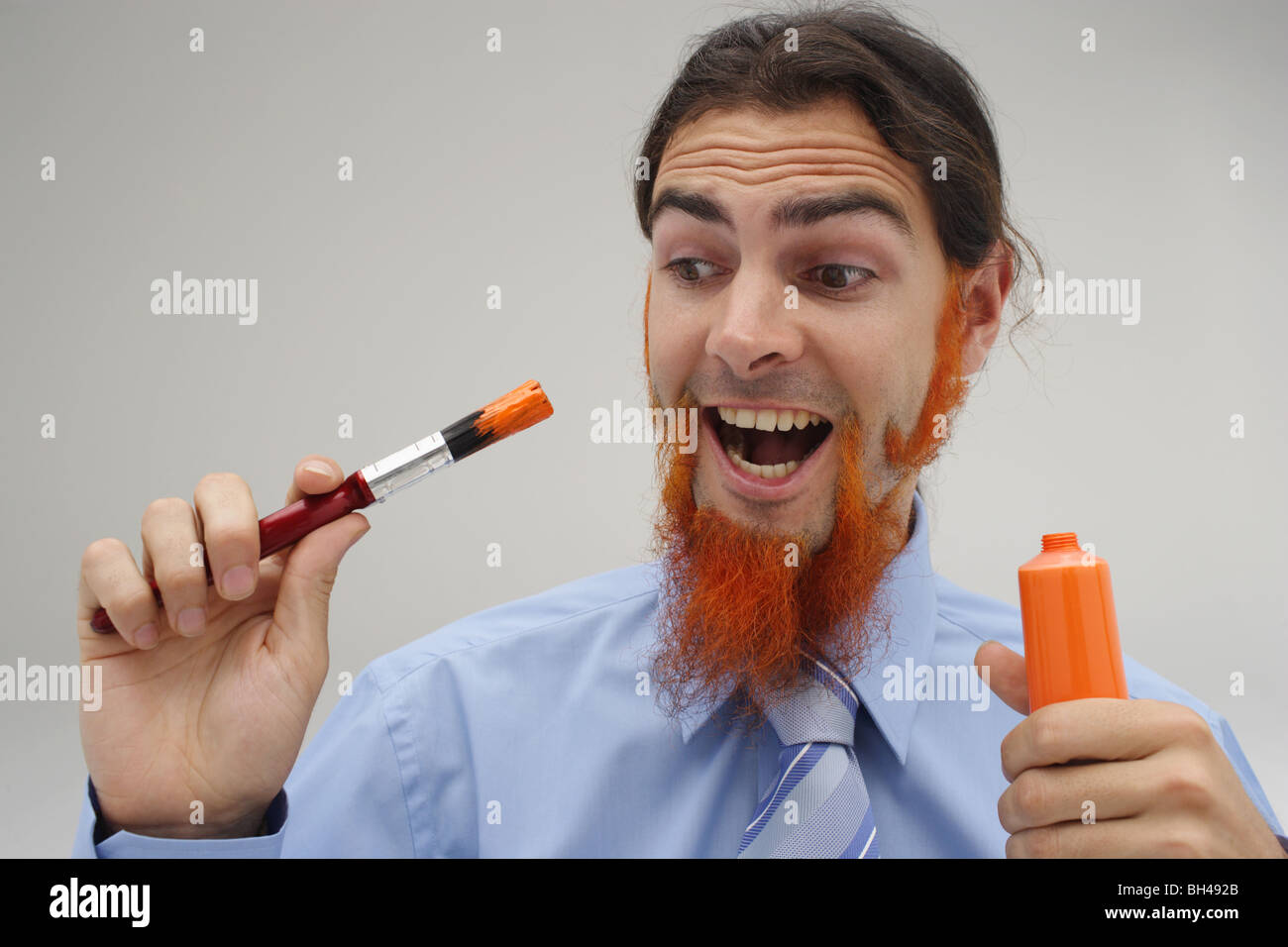 Un jeune homme avec sa barbe peinture peinture orange, rire Banque D'Images