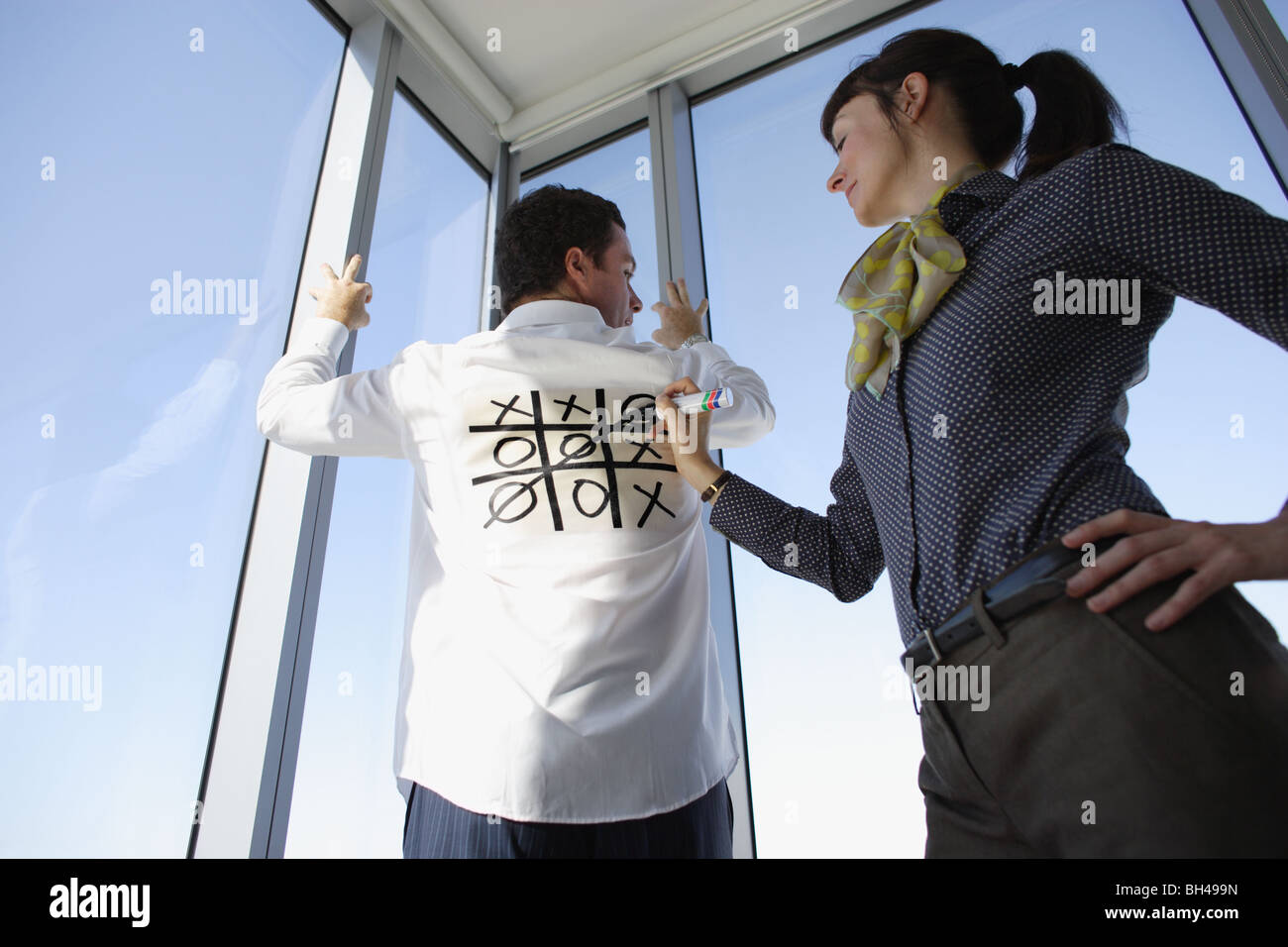 Une femme jouant de croisements et des zéros ( Tic Tac Toe ) sur le dos d'une chemise d'homme d'affaires blanc Banque D'Images