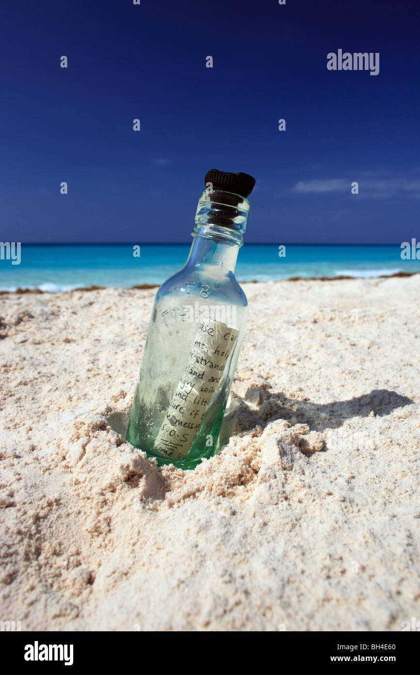 Un message dans une bouteille dans le sable sur une plage tropicale déserte Banque D'Images