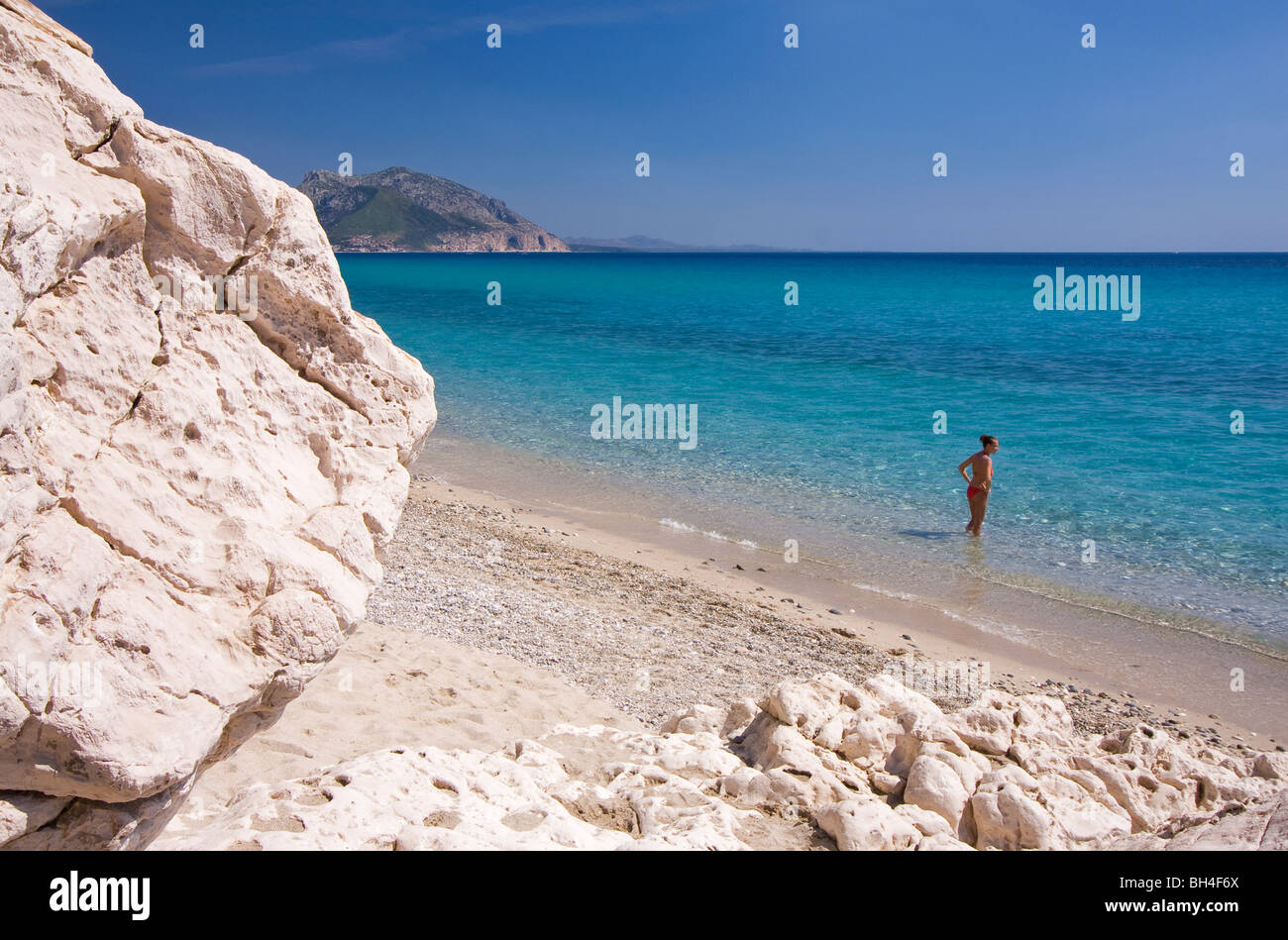 Plage Cala Luna vide, Sardaigne, île de l'Italie. Jeune femme solitaire en eau bleu clair dans la baie de Cala Luna, Mer Méditerranée. Banque D'Images