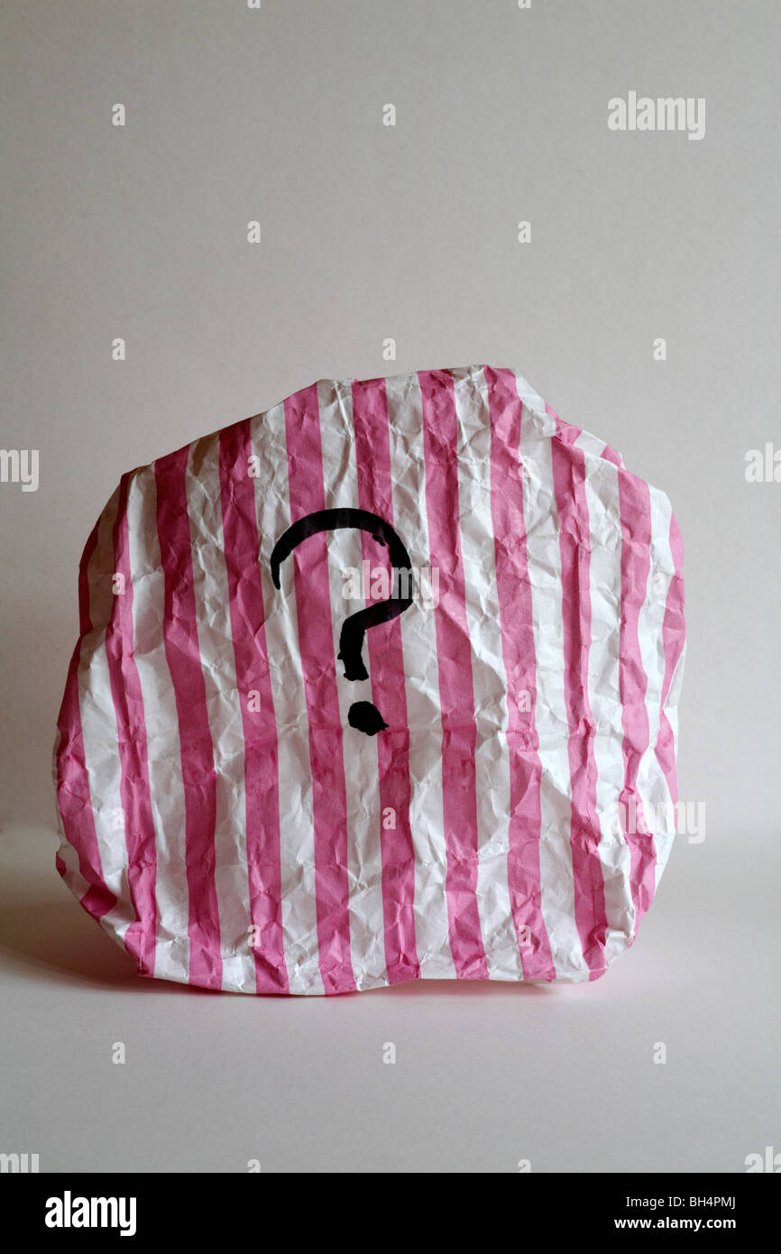 sac en papier à rayures roses et blanches avec point d'interrogation - concept d'intrigue mystère surprise Banque D'Images