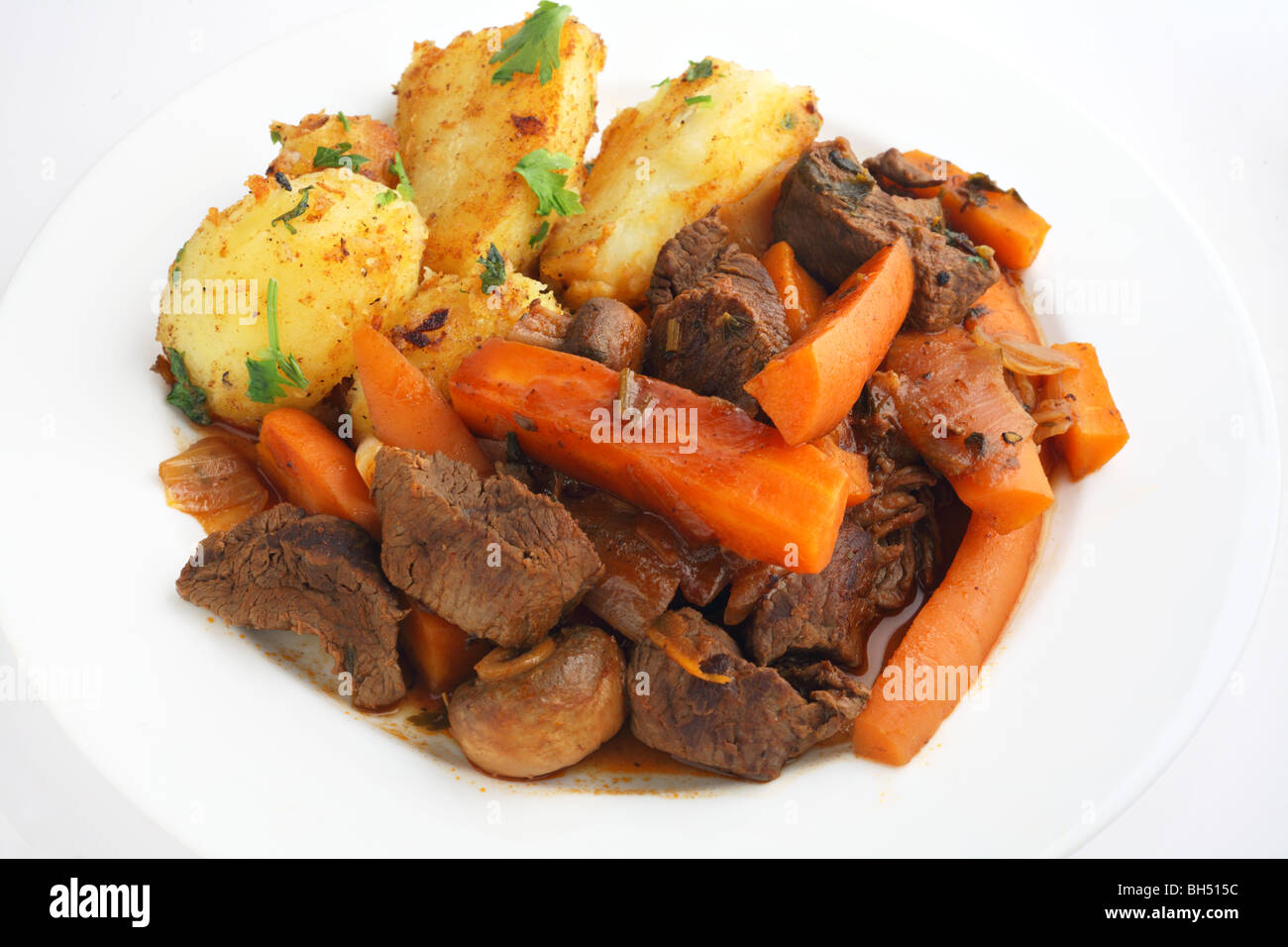 Un plat de viande de style français et de carottes aux herbes ragoût, servi avec pommes de terre sautées garnie de persil haché Banque D'Images