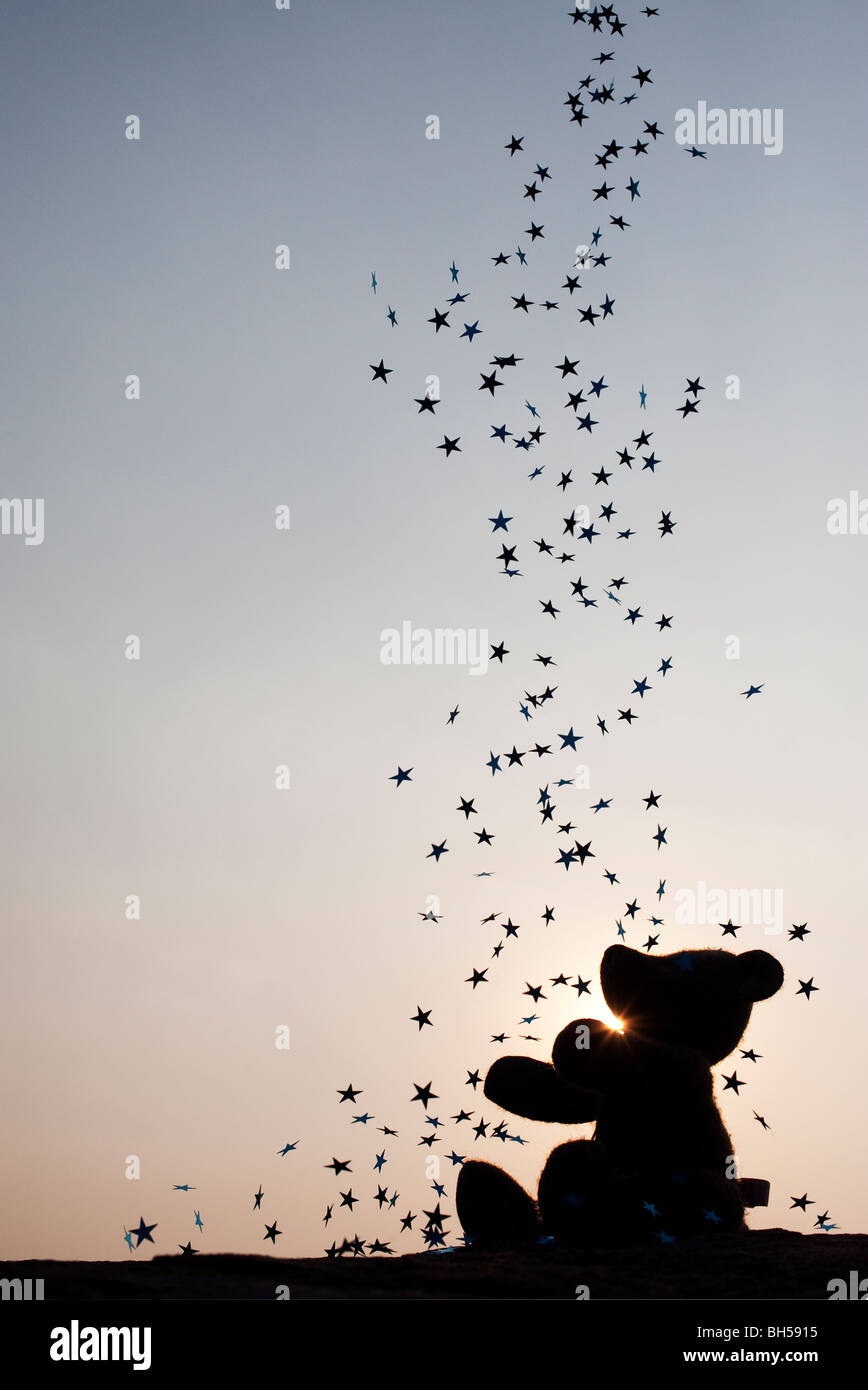 Teddy bear catching falling stars silhouette Banque D'Images