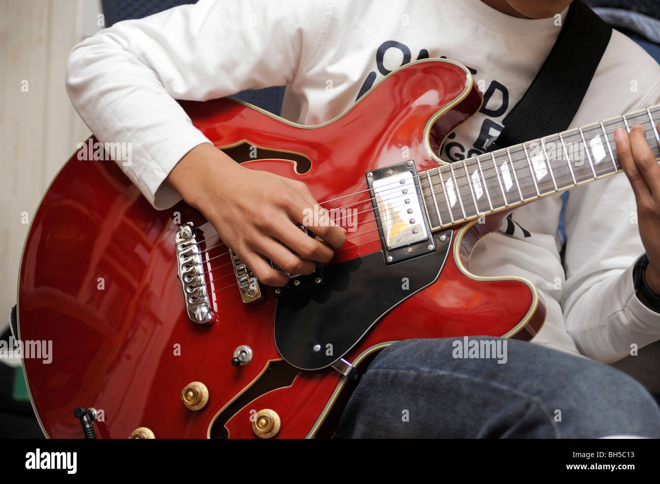 Garçon jouer avec une guitare jazz Aria, style Gibson 335 Banque D'Images