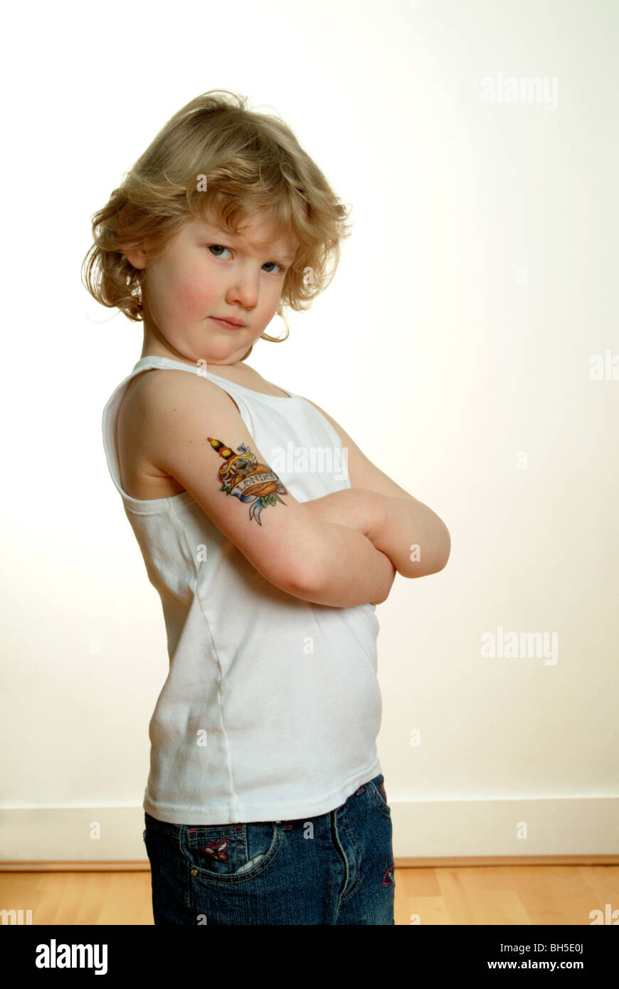 Une jeune fille de race blanche se tient avec ses bras croisés avec un faux tatouage de Londres sur son bras supérieur. Banque D'Images