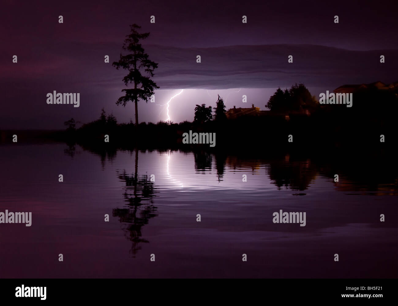 Orage lieux peu après le coucher du soleil la création de teinte pourpre avec la silhouette du sapin reflétant dans l'eau et le littoral voir Banque D'Images