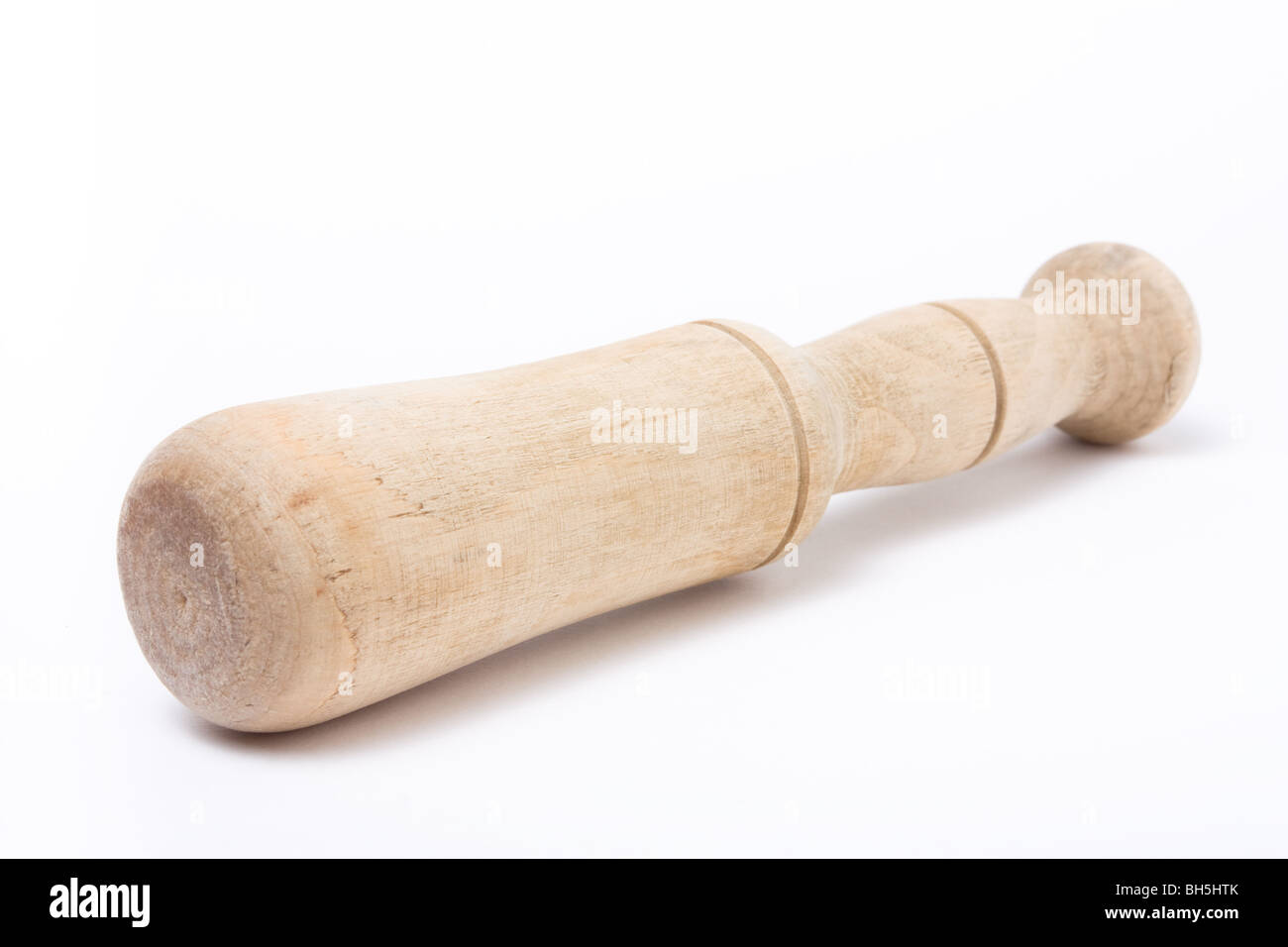 Ancien outil de meulage pilon en bois usés contre isolé sur fond blanc. Banque D'Images