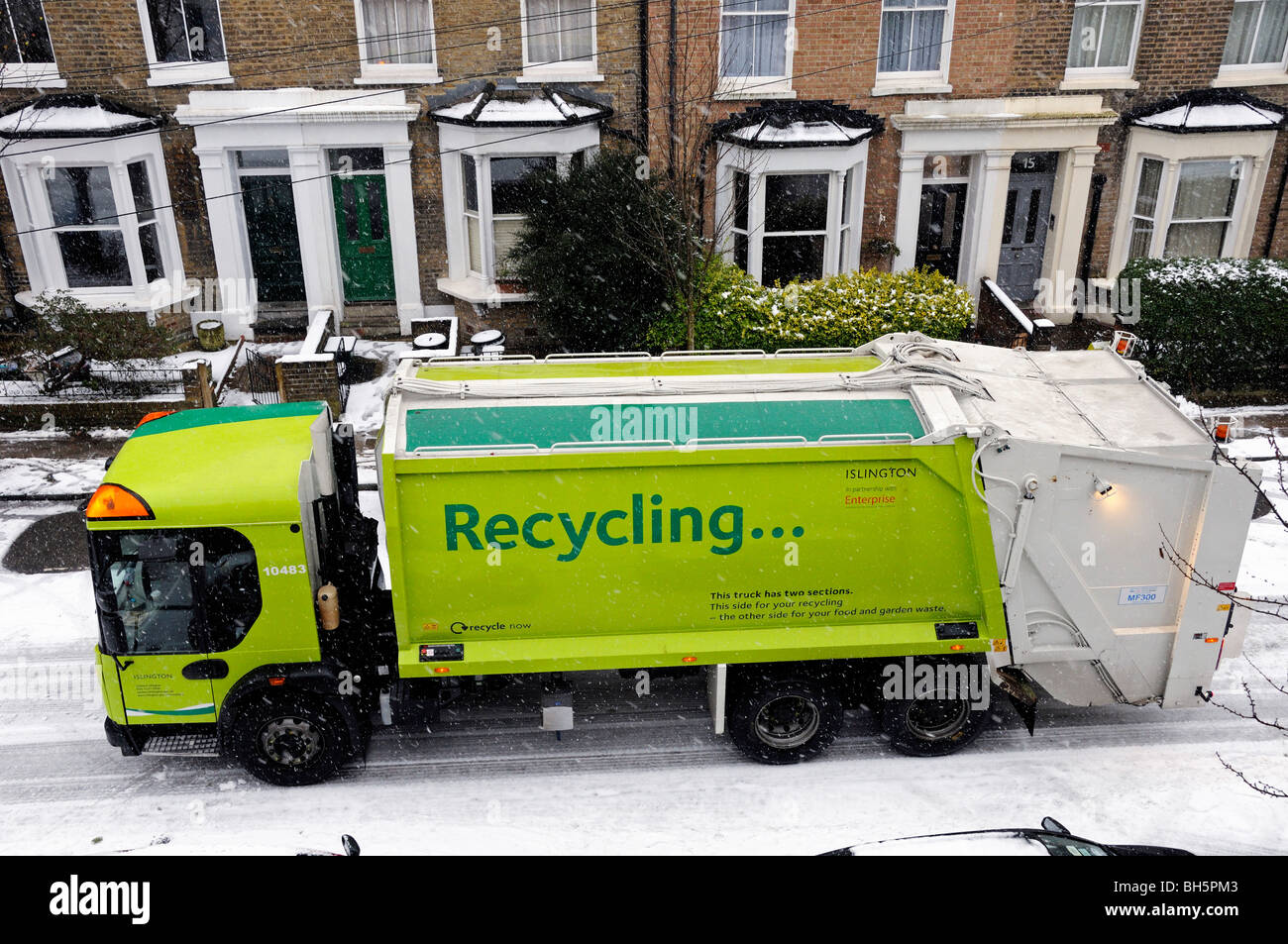 Camion de recyclage ou camion avec slogan de recyclage sur le côté dans la neige, avec des maisons derrière Bryantwood Road Holloway N7 Islington Londres Angleterre Royaume-Uni Banque D'Images