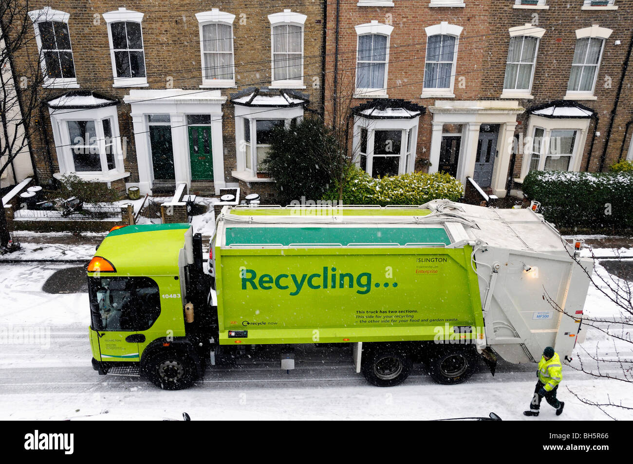 Camion de recyclage ou camion dans la neige avec connexion de recyclage sur le côté et maisons derrière, employé du conseil Bryantwood Road Holloway Islington Londres Angleterre Royaume-Uni Banque D'Images