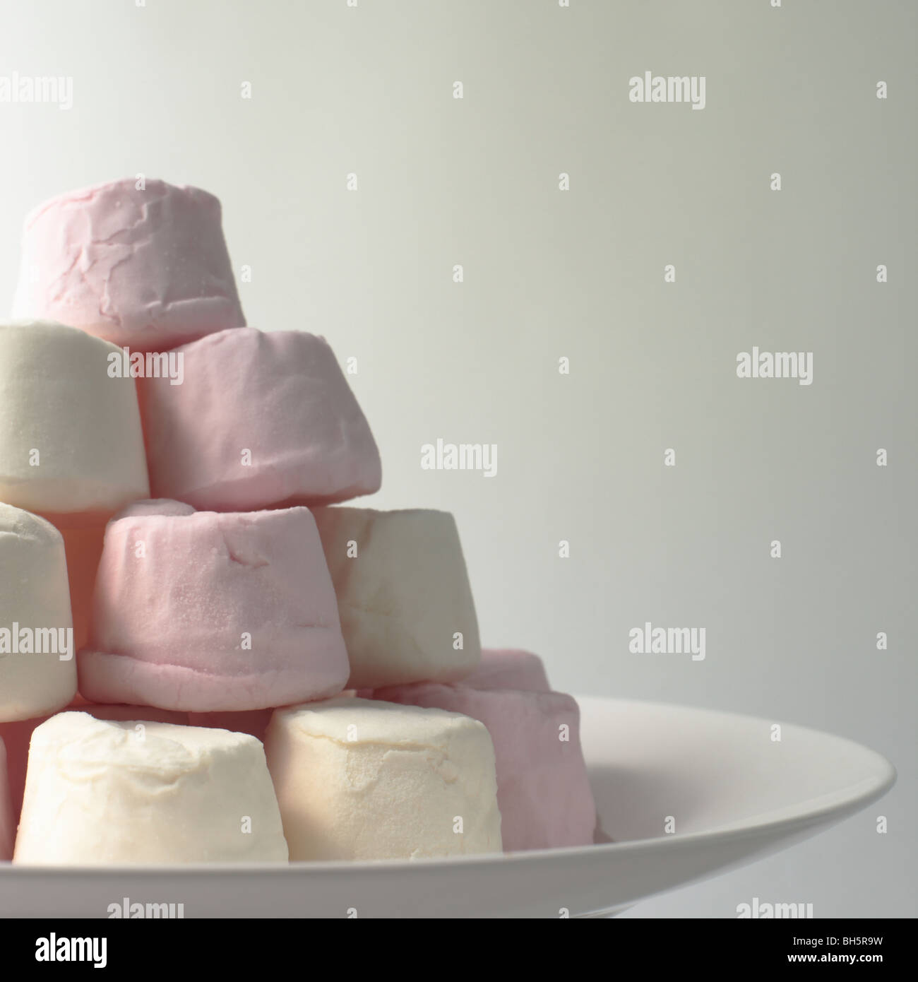 Les guimauves rose et blanc empilés sur une assiette Banque D'Images