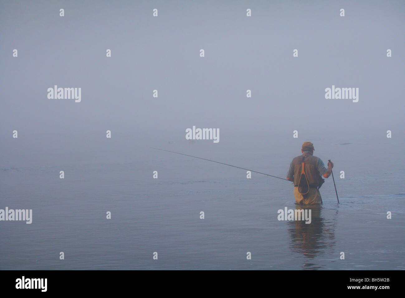 FLY FISHERMAN WADING IN RIVER PORTANT canne à mouche un épais brouillard MAUVAIS TEMPS Banque D'Images